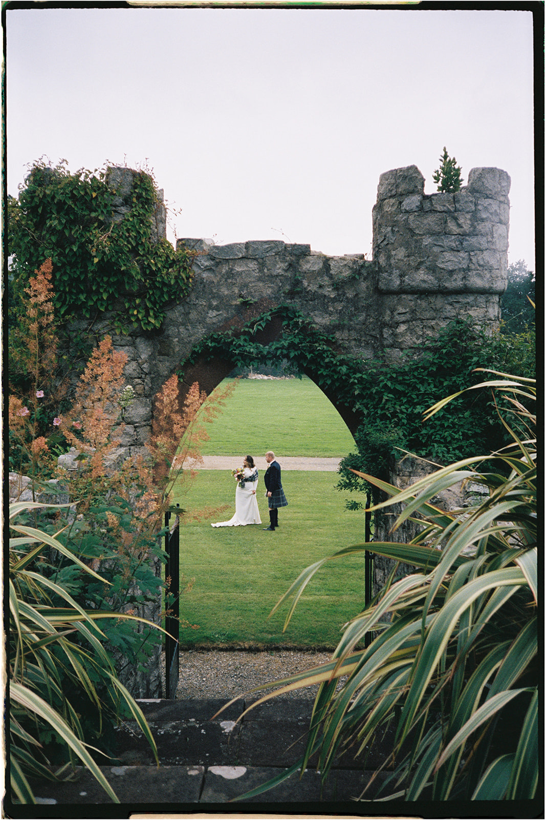 Bride and groom framed by stone archway on the Isle of Arran on 35mm film