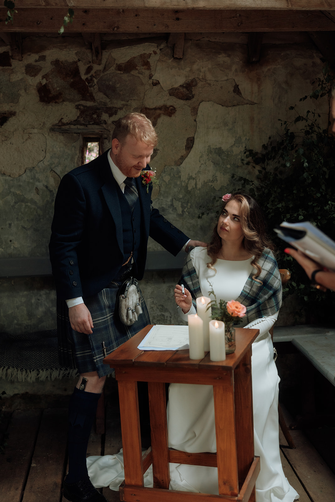 Bride and groom with celebrant signing paperwork during Isle of Arran elopement at Loch Iorsa.