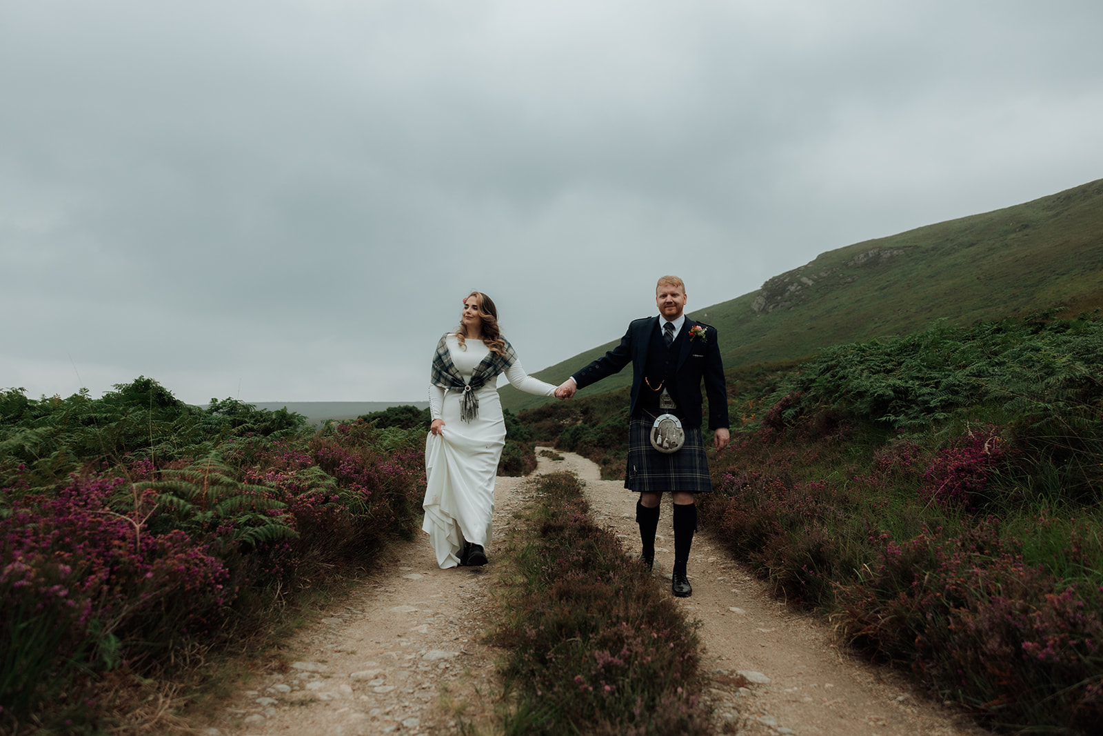 Bride and groom walking side by side along hillside during Isle of Arran elopement.