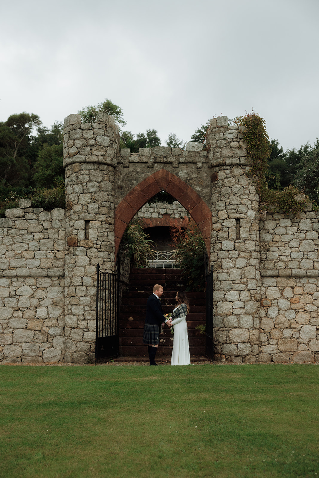 Bride and groom standing at stone archway during Isle of Arran elopement.