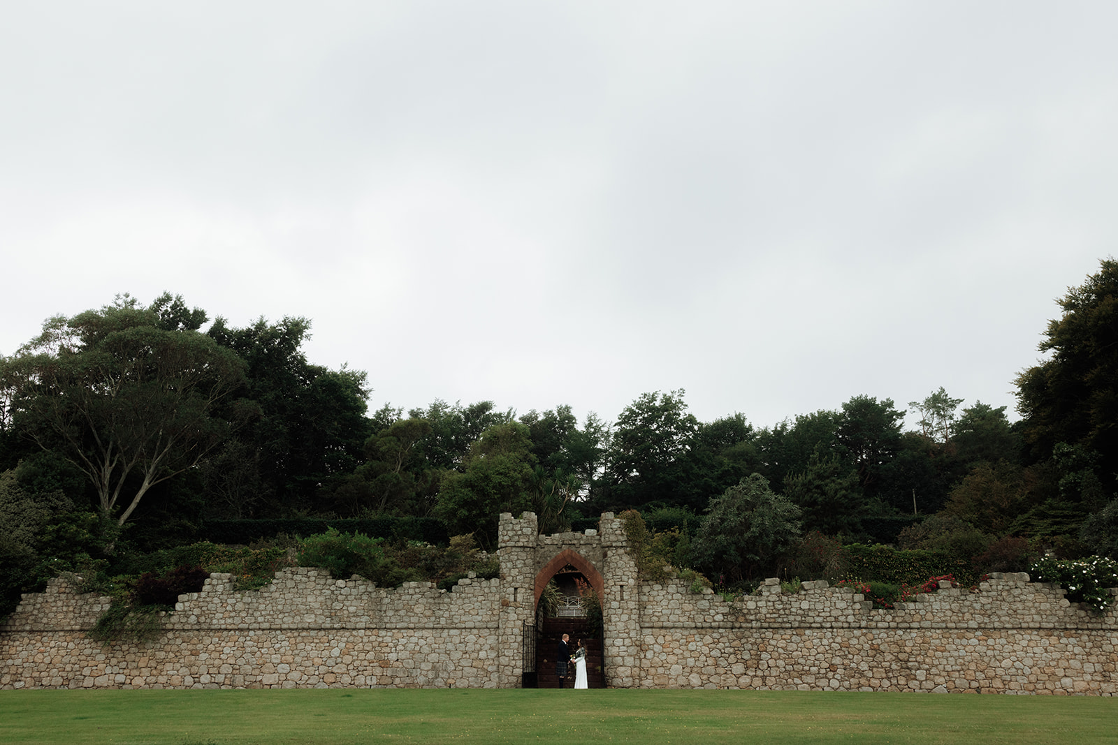 Bride and groom standing beneath brick archway during Isle of Arran elopement.