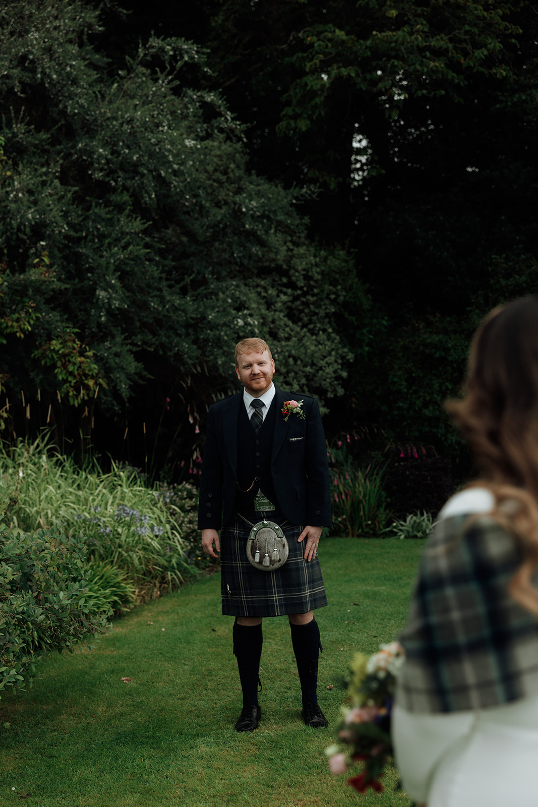 Groom portrait with bride blurred in foreground during Isle of Arran elopement.