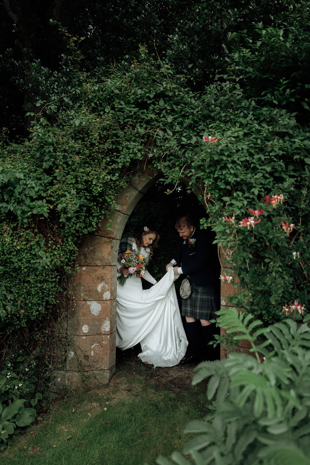 Bride and groom walking out of stone archway during Isle of Arran elopement.