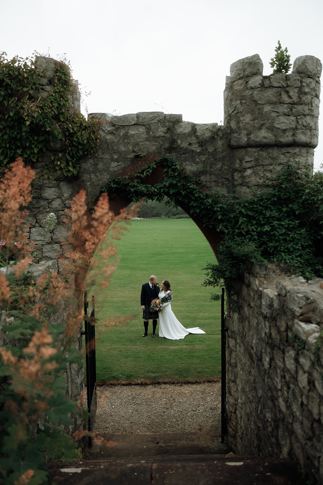 Bride and groom standing together under stone archway during Isle of Arran elopement.