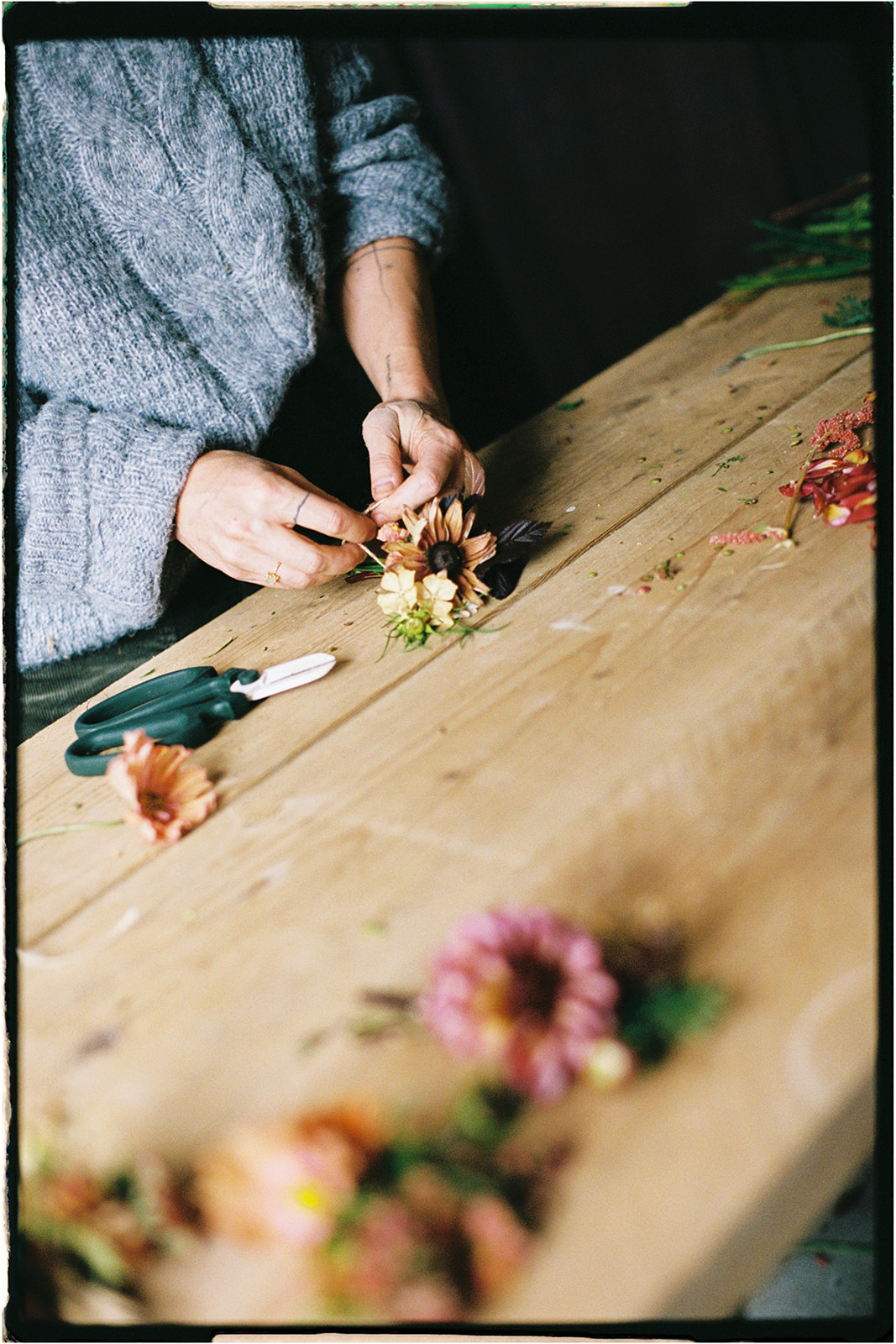 Tupelo Tree florist creating wild floral arrangements by hand on a rustic wooden table, captured on 35mm film in Scotland.