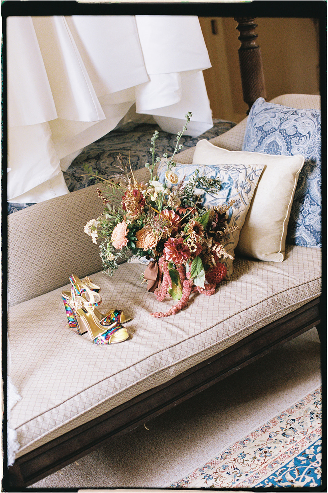 Wedding bouquet and shoes arranged on a vintage sofa in soft light inside Winton Castle.